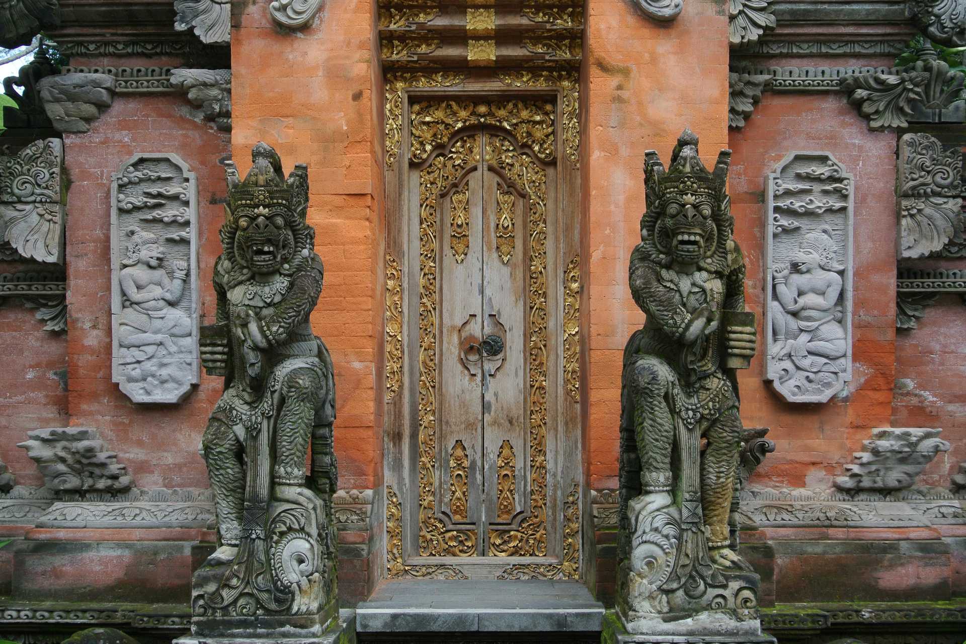 Capturing the ornate entrance of a Balinese temple in Ubud with detailed stone carvings and golden accents.