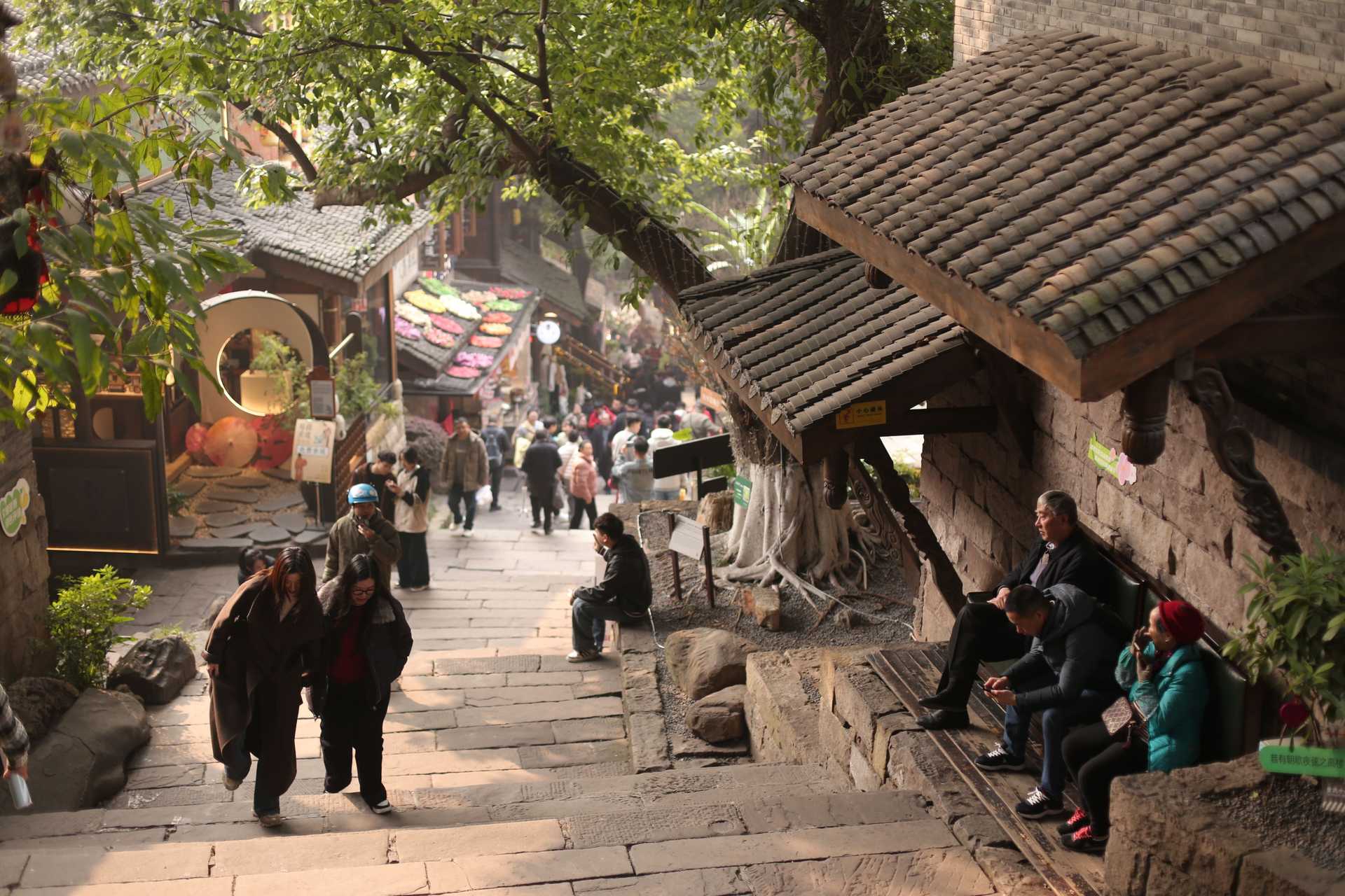 Bustling street scene in an ancient town with people, shops, and traditional architecture.